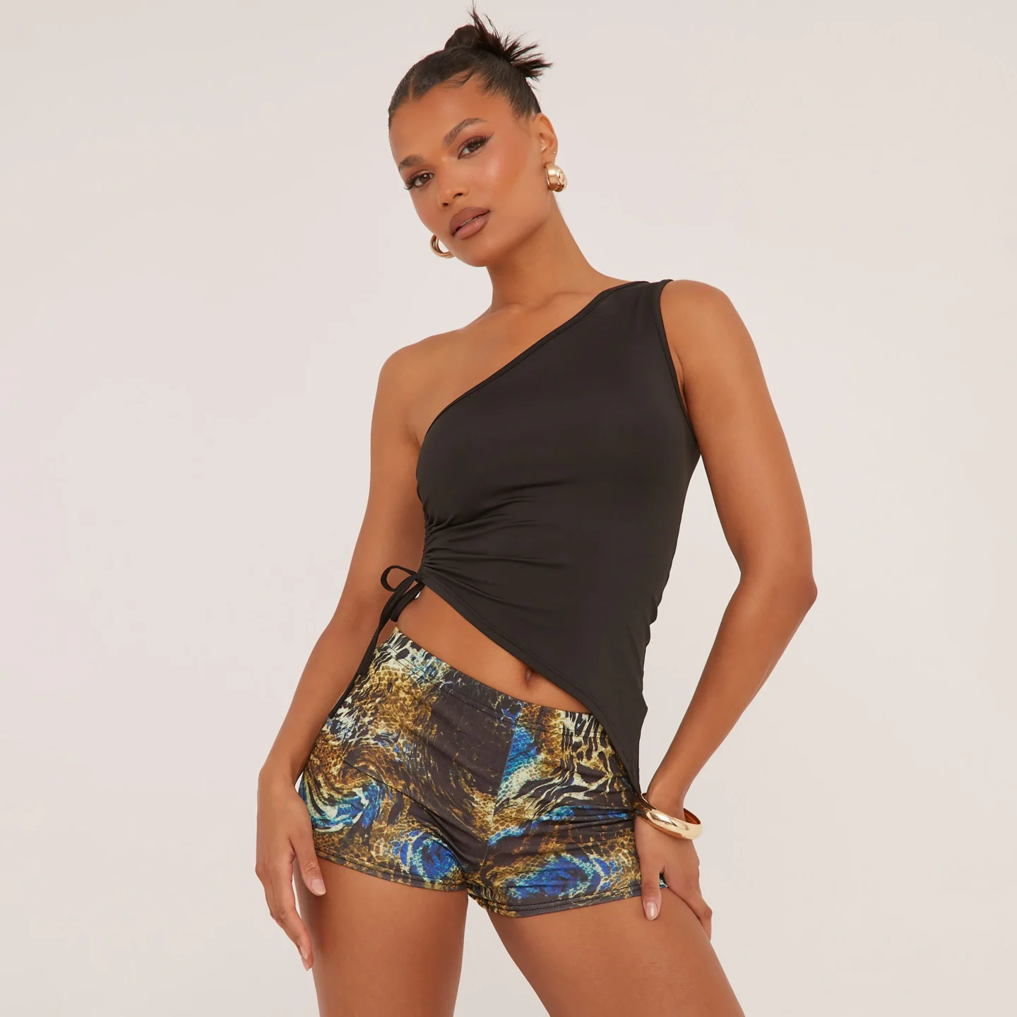 Blue animal pint hot pants in a mise-rise fit. Model wears with a black one shoulder top. 