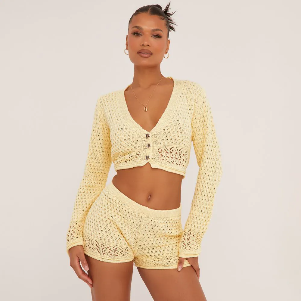 a yellow crochet cardigan with button up front and a v neckline. The cardigan is cropped and has long sleeves. 