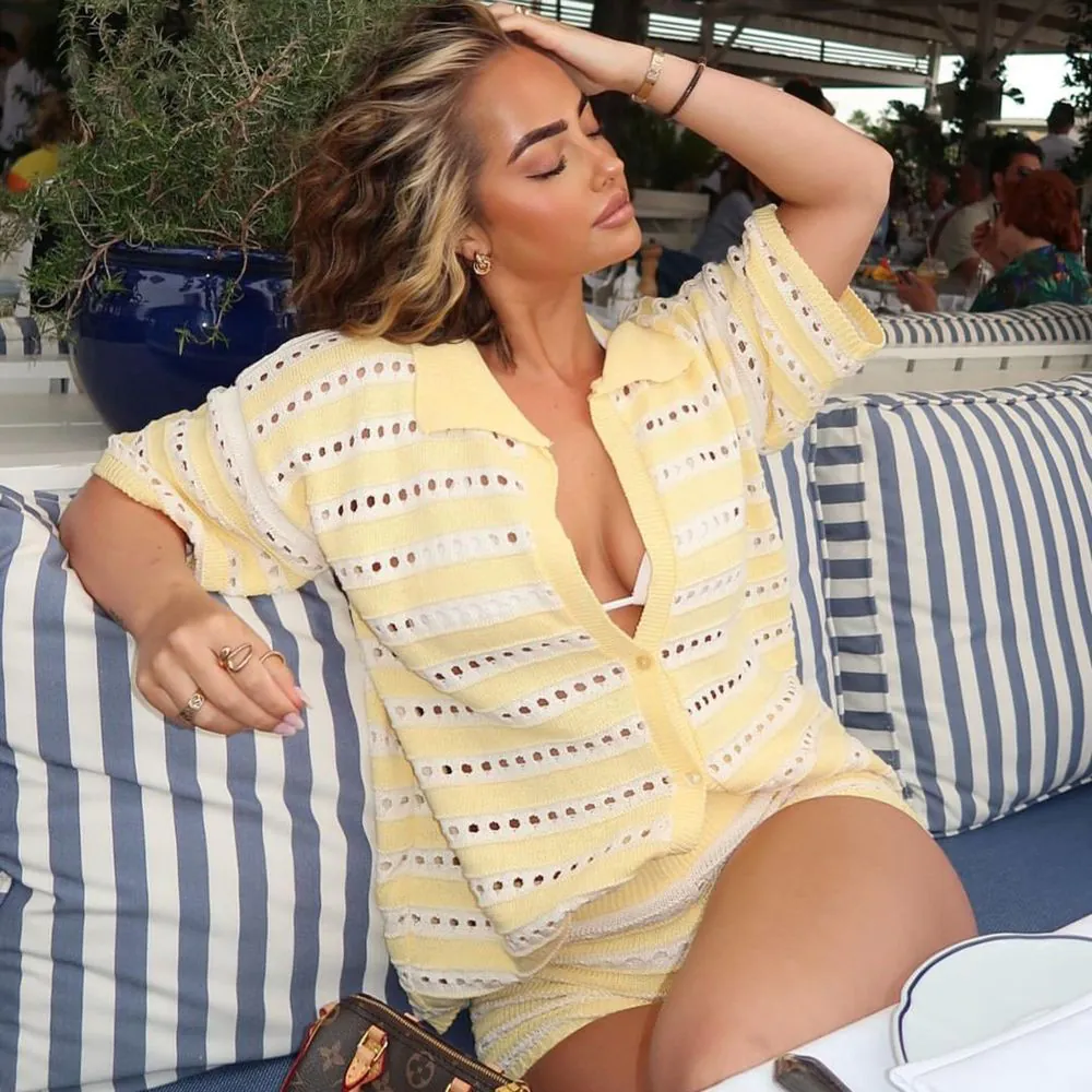 A crochet co-ord in yellow and white stripes. The top is a collared shirt style, and the sorts are low rise micro shorts. The woman is wearing a white bikini top under the set.